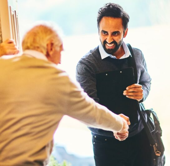 Care worker arriving at clients house, shaking clients hand at the front door.